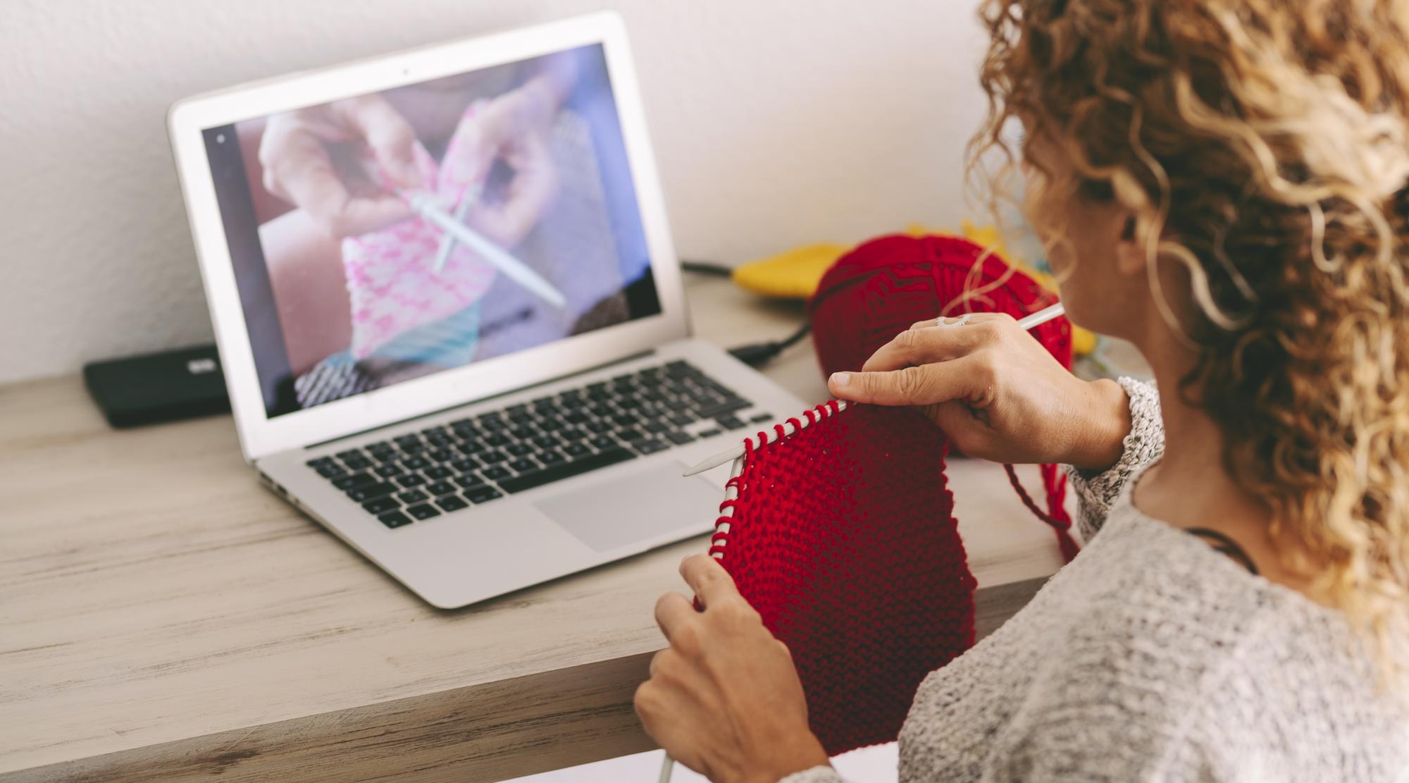 Insegnante che dimostra tecnica di ricamo davanti a laptop
